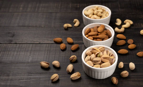 Almonds with cashews and pistachios on a dark wooden background