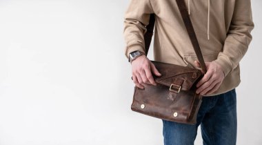 Açık arkaplanda kahverengi deri çantalı bir adam.