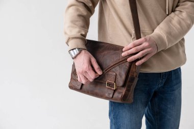Açık arkaplanda kahverengi deri çantalı bir adam.