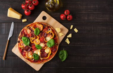 Siyah ahşap arka planda mozzarella ve salamlı pizza.