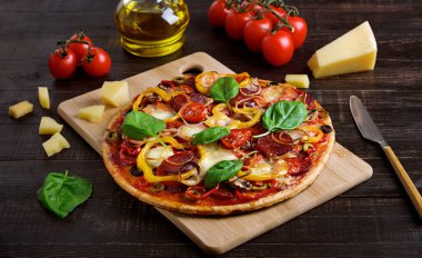 Siyah ahşap arka planda salamlı ve mozarellalı pizza.