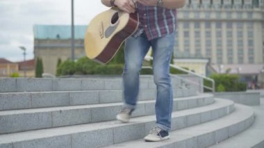 Beyaz adam şehir merdivenlerinden çıkıyor, şapkasını çıkarıyor ve gitar çalmaya başlıyor. Sokak müzisyeninin portresi yaz günü açık havada para kazanmak için gösteri yapıyor. Yalvarma kavramı.