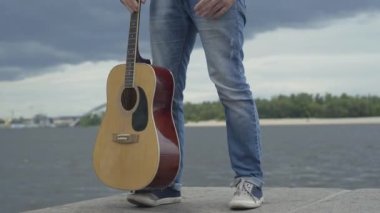 Beyaz adamın bacakları setin üzerinde ritm tutturuyor. Nehir kıyısında durup müzik dinleyen tanınmamış bir müzisyen. Sanat ve hobi konsepti.
