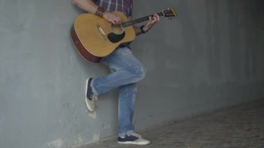 Yer altında duvarda durup gitar çalan tanınmamış bir sokak müzisyeni. Erkek fakir Kafkasyalı dilenci şehir merkezinde gösteri yapıyor. Yoksulluk kavramı.