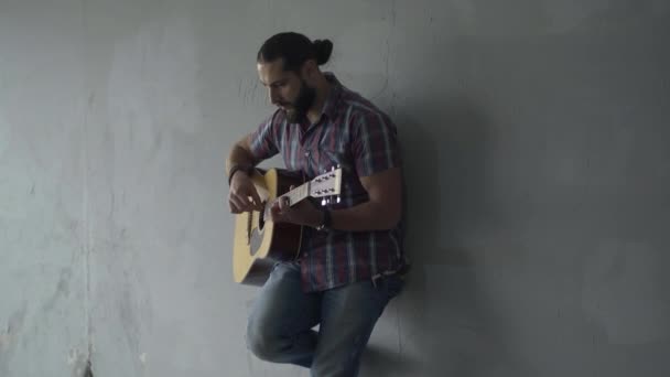 Absorbed guitarist standing against grey wall in underground crossing and playing guitar. Portrait of Caucasian musician performing outdoors. Art and begging concept. — Stock Video