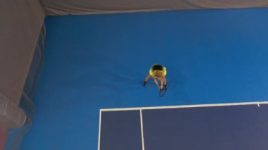 Bronzlaşmış ince beyaz bir kadının kapalı sahada tenis oynaması. Spor salonundaki rekabetçi oyunda kendine güvenen genç sporcu kadın eğitimi. Spor ve sağlıklı yaşam tarzı.
