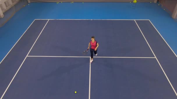 Amplia vista aérea de tiro de confiada deportista caucásica sirviendo pelota en tenis grande. Atlética mujer adulta de entrenamiento en el gimnasio jugando juego competitivo. Concepto de confianza y deporte profesional. — Vídeos de Stock