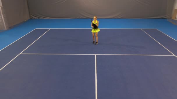 Extreem breed schot van zelfverzekerde mooie sportvrouw slaan bal met racket op indoor tennisbaan in de sportschool. Portret van jonge blanke geconcentreerde vrouw training binnen. — Stockvideo