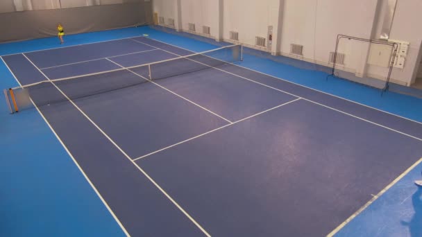 Extreme wide shot of tennis court in gym with two professional slim Caucasian women hitting ball with rackets. Top angle view of confident sportswomen training big tennis game. — Stock Video