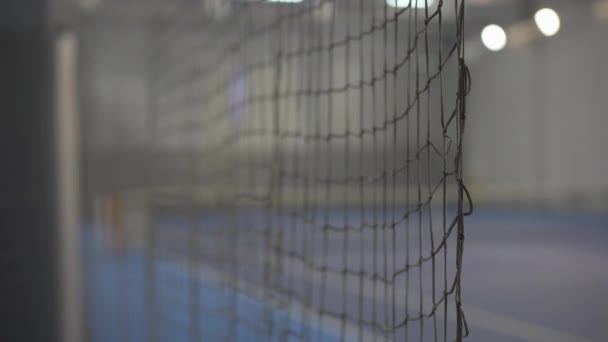 Σίγουρη αθλήτρια μπαίνει σε κλειστό γήπεδο τένις μέσω διχτυού και φεύγει. Νεαρή αδύνατη καυκάσια γυναίκα προπονείται σε κλειστό γυμναστήριο. Αθλητική έννοια. — Αρχείο Βίντεο