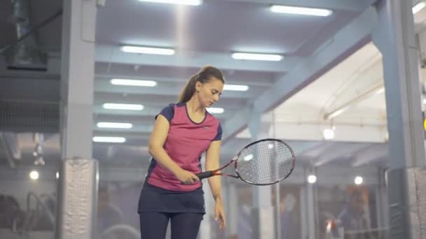 Koncentrált sportoló teniszlabdát szolgál fel a tornateremben. Egy koncentrált, magabiztos kaukázusi nő portréja, aki a belső udvarban edz. Profi női játékos edzés. — Stock videók