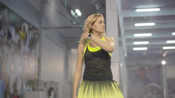 金发碧眼的女运动员在大型网球比赛中发黄球.一个自信的、专注的高加索女人在体育馆里玩体育比赛的画像。锻炼和专业体育概念. — 图库视频影像
