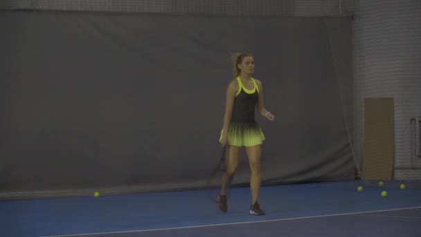 Breed schot van professionele sportvrouw slaan gele bal met racket. Portret van jonge slanke zelfverzekerde blanke vrouw die binnen groot tennis speelt in de sportschool. Sport en levensstijl. Schieten achter het net. — Stockvideo