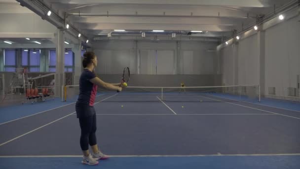 Széles kép két profi teniszező ütő sárga labdát ütő ütő ütő tornaterem. Magabiztos kaukázusi sportoknői képzés zárt térben a versenyképes sportban. — Stock videók
