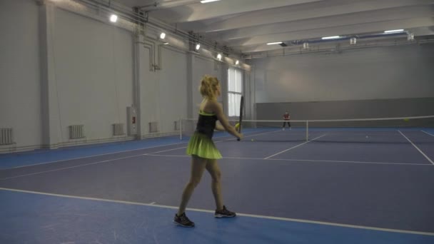Live camera follows big tennis game of two confident women. Professional sportswomen training in gym on indoor court. Slim Caucasian women playing competitive game. — Stock Video