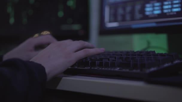 Primeros planos de las manos del joven hombre caucásico escribiendo en el teclado de la computadora. Programador masculino irreconocible codificando en la oscuridad en interiores. Hacker usando PC para robar información o hackear datos de la cuenta. — Vídeos de Stock