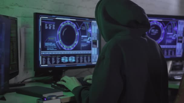 Joven hacker caucásico con capucha usando múltiples computadoras para robar información o minería de datos. Barbudo absorbido hombre escribiendo en el teclado y mirando las pantallas. Concepto de seguridad en Internet. — Vídeos de Stock