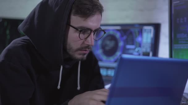 Retrato de jovem focado hackear web site ou lançar vírus de computador usando rede global. Programador ou hacker caucasiano concentrado em óculos e dados de mineração de capuz na Internet. — Vídeo de Stock