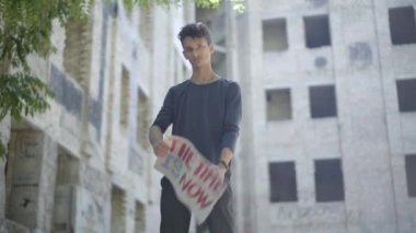 Terk edilmiş bir şehirde güneş ışığında poz veren ciddi bir melez. Sosyal eşitsizliğe ve önyargılara karşı savaşan kendine güvenen protestocuların portresi artık bayrak oldu. Göç.