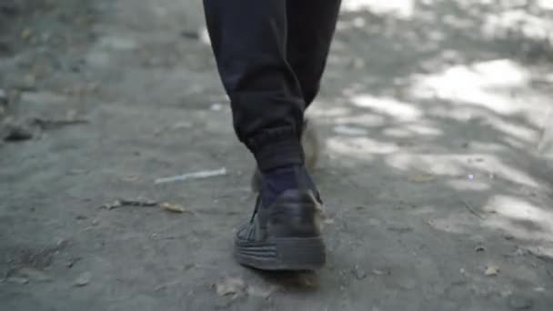 A câmera segue os passos do homem andando ao longo do gueto abandonado com seringas e pílulas por aí. Refugiado masculino irreconhecível que vive em ruínas ou favela. Conceito de pobreza. — Vídeo de Stock