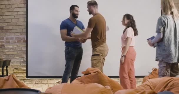 Genç erkekler ve kadınlar, sıradan bir iş arkadaşlığı dersinden sonra gülümseyen iş koçlarının elini sıkarlar. Seyircilere veda eden başarılı bir Orta Doğulu. Sinema 4k ProRes Merkezi. — Stok video