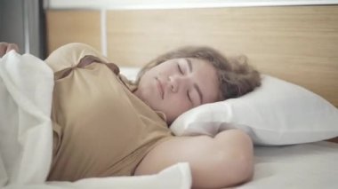 Beyaz yastıkta uyuyan gevşemiş tombul kadının yakın çekimi. Tasasız beyaz bir kadının portresi sabahları yatak odasında dinleniyor. Boş zaman ve rahatlama..