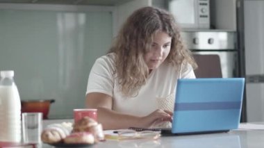 Sabahları dizüstü bilgisayarda internette sörf yapan ve notlar yazan kendine güvenen tombul bir kadın. Salgın karantina sırasında evden çalışan şişman güzel bir kadının portresi. Serbest konsept.