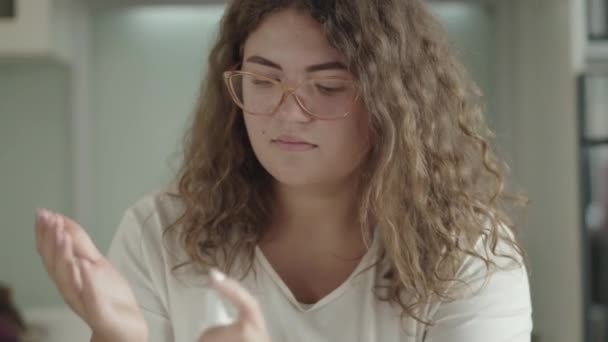 Портрет кавказької жінки, яка перед споживанням яблука, дезінфікує руки санитизатором. Перед їдою молода панянка в окулярах очищає пальми. Пандемічний спосіб життя ковед-19. — стокове відео