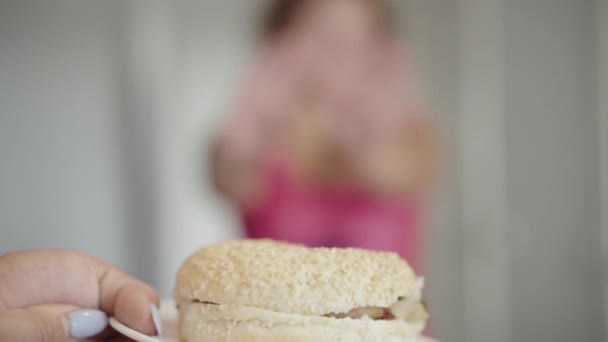 Close-up van hamburger op bord met wazig overgewicht vrouw zwaaiende handen gebaren nee. Onherkenbaar plus-size blanke dame die weigert junk fastfood te eten. Diëten en obesitas concept. — Stockvideo