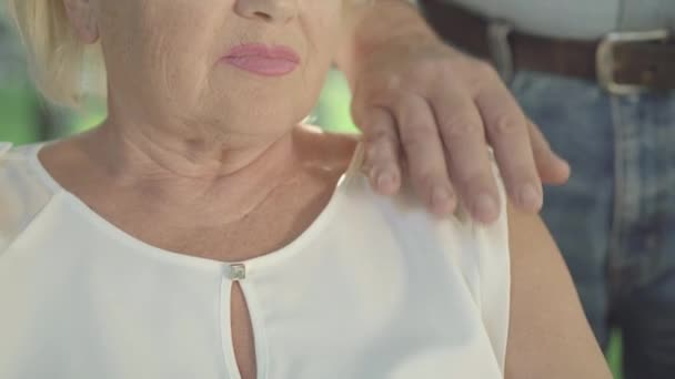 一个无法辨认的老妇人牵着老人的特写镜头。一对夫妇的白人退休人员在阳光灿烂的夏季公园室外。支持和爱的概念. — 图库视频影像