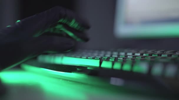 Gros plan de la main en gant noir tapant sur le clavier de l'ordinateur la nuit en vert clair. Un pirate informatique méconnaissable téléchargeant des virus ou piratant un site Web à l'intérieur. Sécurité des données métier. — Video