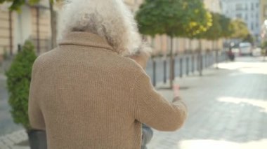 Şehir caddesinde koşup büyükbabaya sarılan gri saçlı adama koşan mutlu çocuk. Güneşli bir günde büyükannesi ve büyükbabasıyla buluşan neşeli beyaz çocuğun portresi. Aile kavramı.