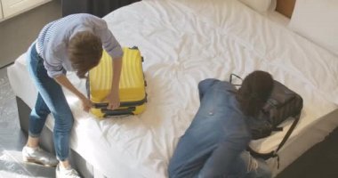 Irklar arası genç çiftin otel odasındaki ya da evdeki bavullarını boşaltma görüntüsü. Afro-Amerikalı erkek ve beyaz kadın, ev gezisinden önce ya da sonra. Turizm ve tatil kavramı.