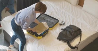 Beyaz bir kadına evinde ya da otel odasında bavul taşıyan Afrikalı Amerikalı bir adama yardım etmenin en iyi görüntüsü. Birlikte seyahat eden pozitif ırklar arası bir çift. Aşk ve eğlence konsepti.