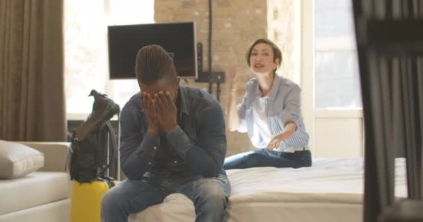 Vred smuk kaukasiske kvinde råben og gesturing i baggrunden som træt keder afroamerikansk mand sidder ved fronten holder hovedet i hånden. Ung interracial par skændes under turen. – Stock-video