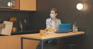 Covid-19 yüz maskeli genç beyaz kadın dükkandan yiyecekle dönen Afro-Amerikalı adam olarak evden internet üzerinden çalışıyor. Farklı ırktan çiftler Coronavirus 'u evde karantinaya alıyorlar..