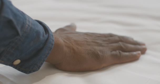 Kamera śledzi młodego Afroamerykanina dotykającego białej pościeli. Nierozpoznawalny turysta cieszący się miękkością hotelowego łóżka. Nieznany inspektor sprawdzający jakość obsługi hotelowej. — Wideo stockowe