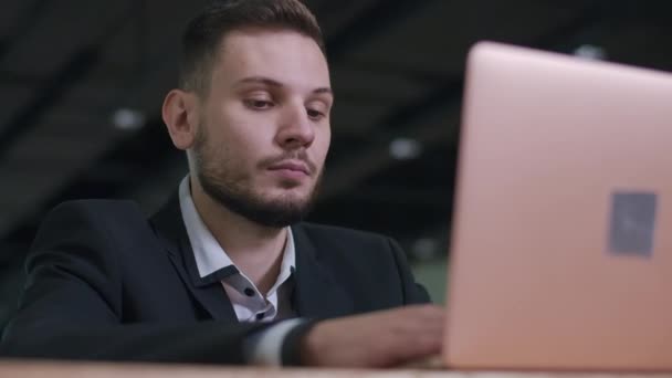 Primo piano di concentrato bell'uomo d'affari barbuto che lavora online su laptop. Ritratto di uomo bruna caucasico sicuro di sé in abito elegante con occhi marroni che navigano su Internet o messaggistica. — Video Stock