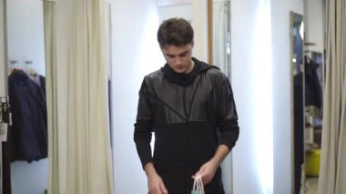 Soyunma odasında dikilip kameraya göz kırpan yakışıklı beyaz adamın portresi. Alışveriş merkezinde poz veren kendinden emin esmer bir erkek..