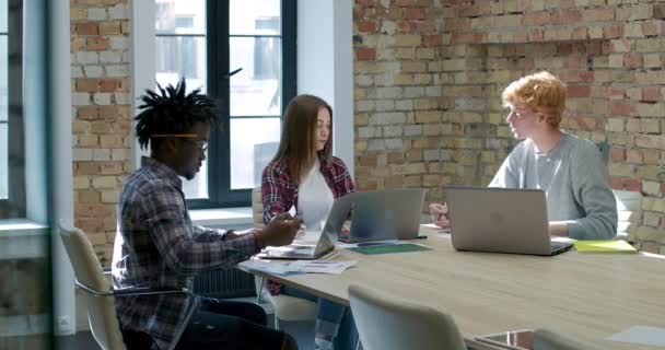 많은 수의 젊은 백인과 아프리카계 미국인 동료들이 노트북을 들고 사무실에 앉아 스타트업의 성공을 분석하고 있습니다. 신뢰 할 수있는 다 민족 팀의 브레인스토밍 모임. 시네마 4k ProRes HQ. — 비디오