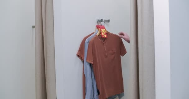 Feliz hombre guapo sacando ropa del camerino y yendo al mostrador de dinero. Retrato de confianza Caucásico comprador masculino comprar equipo en las ventas del Viernes Negro en el centro comercial. Sede del cine 4k ProRes. — Vídeo de stock