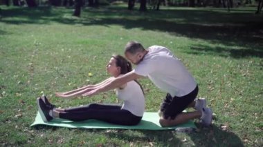 Beyaz bir adamın, kadınların dışarı çıkmasına yardım edişinin yan görüntüsü. Şahsi koçla güneşli çayırda güzel bir sporcu kadın antrenmanı. Spor yaşam tarzı konsepti.