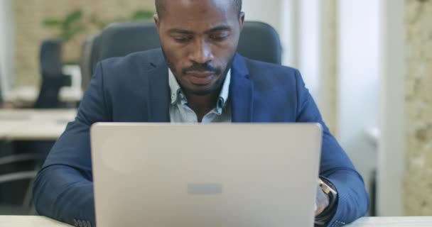 Bonito empresário afro-americano concentrado trabalhando online usando laptop. Retrato do empreendedor focado bem sucedido navegando na Internet ou analisando o mercado de negócios. Cinema 4k ProRes HQ. — Vídeo de Stock