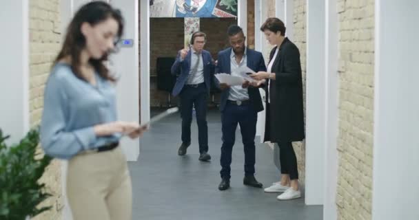 Joyeux jeune homme dans les écouteurs dansant en marchant le long du couloir du bureau saluant ses collègues. Homme d'affaires caucasien joyeux s'amuser au travail. Concept amusant. Siège social Cinema 4k ProRes. — Video