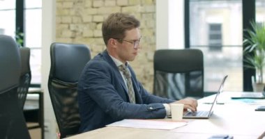 Gözlüklü, dizüstü bilgisayarla çalışan yorgun ve stresli beyaz adamın yan görüntüsü. Çevrimiçi kendine güvenen iş adamının portresi. Aşırı çalışma ve iş kavramı. Sinema 4k ProRes Merkezi.