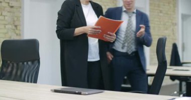 Beyaz adam ve kadın ofise giriyor ve konuşuyorlar. Başarılı bir orta yaşlı CEO oturuyor ve dizüstü bilgisayar açıyor. İş ve takım çalışması konsepti. Sinema 4k ProRes Merkezi.