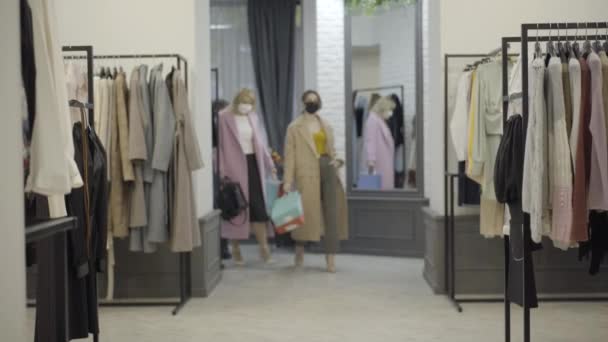 科维德19型面罩中自信的女性带着购物袋走在服装店后离去的全景照片。美丽购物狂用考罗纳威斯黑色星期五买衣服的肖像. — 图库视频影像