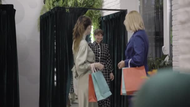Široký záběr sebevědomé ženy s nákupními taškami obdivovat přítele pózování v elegantních stylových šatech. Šťastní bohatí běloši si zkoušejí oblečení v šatně. Nákupní koncept. — Stock video
