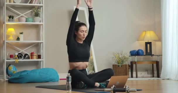 Portrait large de beaux jeunes yogis assis dans la pose du lotus et faisant des exercices de respiration à l'aide d'une leçon vidéo sur ordinateur portable. Slim magnifique femme blanche formation à la maison. Siège social Cinema 4k ProRes. — Video