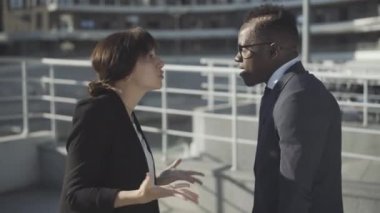 Kızgın meslektaşların dışarıda tartıştıklarını görmek. Stresli beyaz kadın ve Afro-Amerikan erkek güneşli şehir caddesinde el kol hareketi yapıp bağırıyorlar. Genç çok ırklı iş arkadaşlarının iş sorunları.